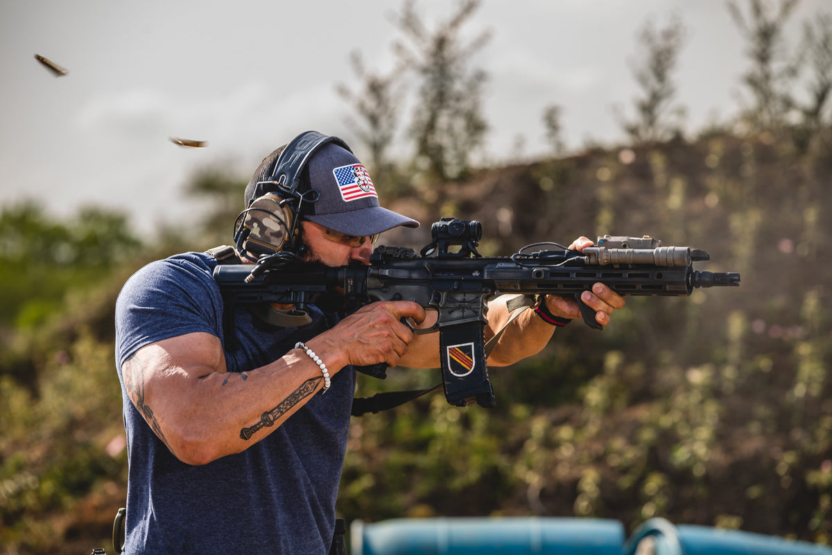 A 2ATG instructor firing a rifle at the range, spent brass in the air